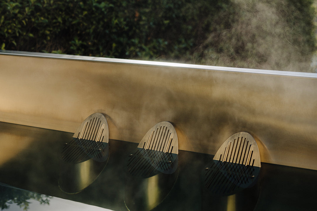 Luxury stainless steel plunge pool emitting steam in tranquil outdoor environment